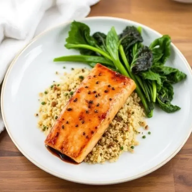 A beautifully plated dish of Miso-Glazed Salmon with quinoa and steamed greens.